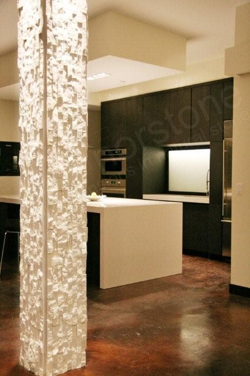 Norstone White Rock Panels installed vertically on a column in a modern themed condo set against a kitchen with dark cabinets and brown concrete stained floors